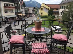 A balcony with a round table, two chairs, and a potted plant.