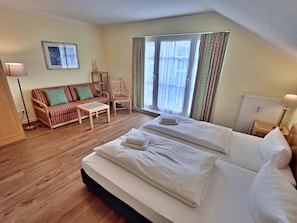 A hotel room with a bed, a sofa, a chair, a table, and a window with curtains.