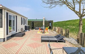 Eine Terrasse mit Gartenmöbeln, einem Grill und einem überdachten Sitzbereich.
