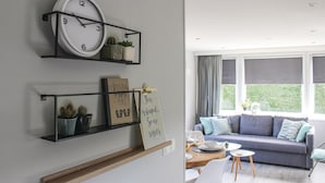 Una sala moderna con un sofá gris, una mesa de centro de madera y un comedor con una mesa redonda pequeña y sillas.