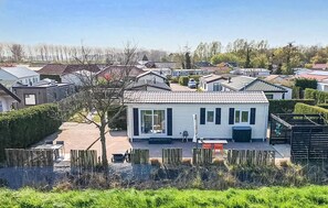 Ein Wohngebiet mit einem weißen Haus, einem Ziegeldach, einem eingezäunten Garten und blauem Himmel.