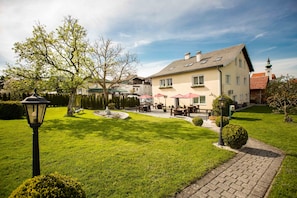 A hotel with a well-maintained lawn, outdoor seating area, and a traditional architectural style.