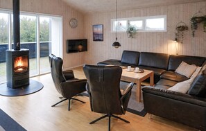 A cozy living room with a wood-burning stove, leather furniture, and a TV mounted on the wall. - Gorgeous home in Tarm with sauna (Tarm)
