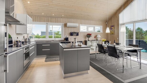A modern kitchen with a central island, built-in appliances, and large windows. - Gorgeous home in Tarm with sauna (Tarm)
