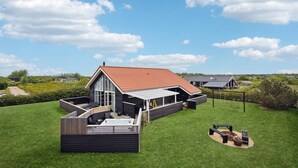 A modern house with a large deck, a fire pit, and a well-maintained lawn. - Gorgeous home in Tarm with sauna (Tarm)
