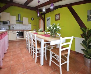 A kitchen with a dining table, chairs, a clock, and a plant.
