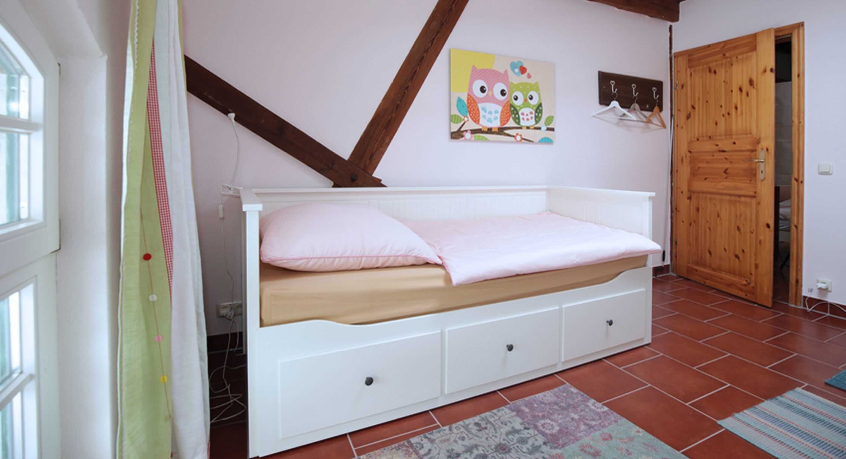 Un dormitorio con una cama blanca, techo de madera, un cuadro colgado en la pared y una puerta de madera.