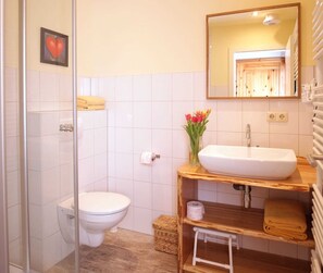 Un baño con inodoro, lavamanos, espejo y cabina de ducha.