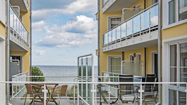 Ein Balkon mit Meerblick, ausgestattet mit einem Tisch und Stühlen.