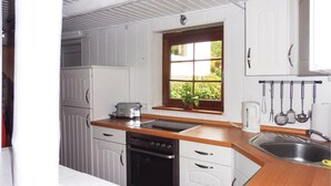 A compact kitchen with white cabinets, a wooden countertop, a built-in oven, a dishwasher, and a window with a view of greenery. - 2 bedroom nice home in Schwalenberg (Schwalenberg)