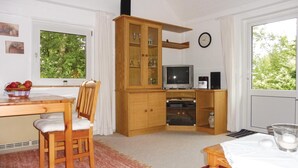 A cozy room with a wooden dining table, a chair, a television, and a cabinet with glass doors. - 2 bedroom nice home in Schwalenberg (Schwalenberg)