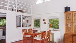A dining area with a wooden table and chairs, a red rug, and a view of greenery through the windows. - 2 bedroom nice home in Schwalenberg (Schwalenberg)