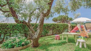 Ein Garten mit Baum, Spielgerät und Tisch mit Stuhl.