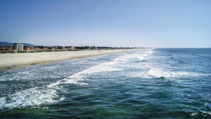 Ein Strand mit freiem Blick auf das Meer und einer entfernten Küste mit Gebäuden.