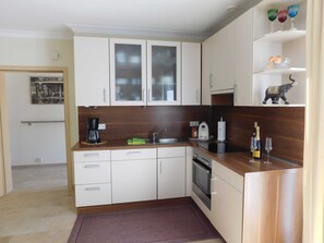 A compact kitchen with white cabinets, a coffee maker, a toaster, and a wine bottle. - Apartment am Rosengarten - Rosengarten (Füssen)