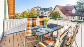 Een balkon buiten met een tafel, stoelen en een tijdschrift.