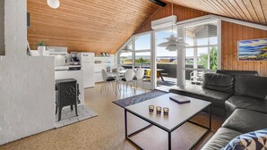 Een moderne keuken met een houten plafond, een eethoek met een tafel en stoelen, en een zithoek met een bank en salontafel.