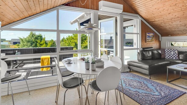 Een moderne loft met een hoge nok, grote ramen, een eethoek en een gezellige zithoek.