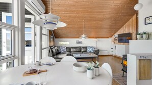 Een moderne keuken met een centraal eiland, een eethoek met een ronde tafel, en een gezellige zithoek met een bank.