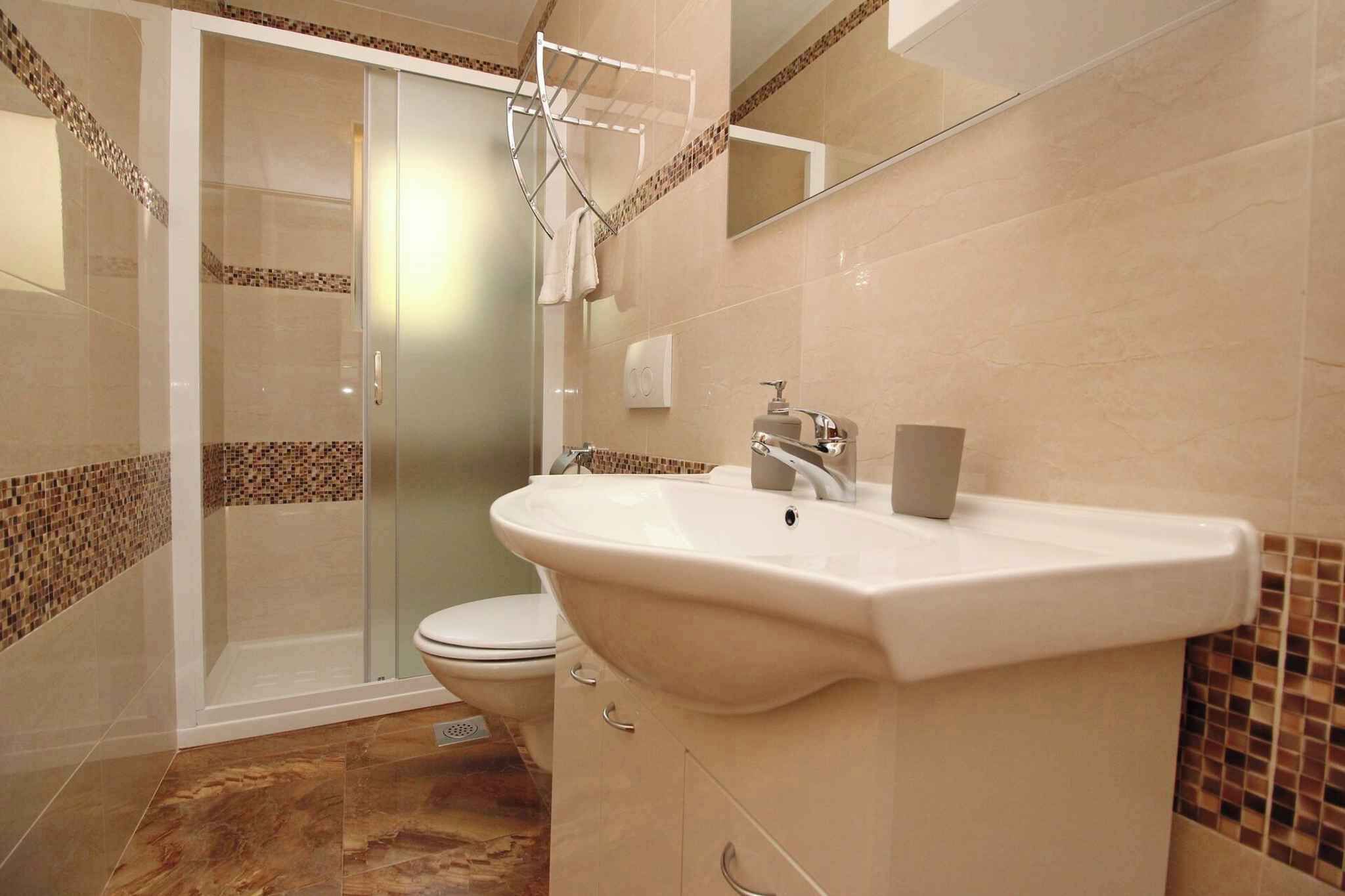 A bathroom with a glass shower enclosure, a white sink with a mirror, and a toilet.