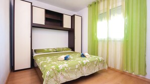Camera da letto con un letto, tende verdi e pavimento in legno.