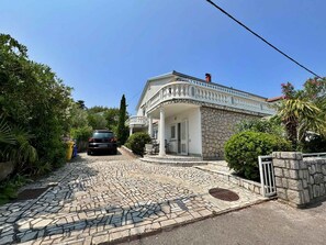 A stone house with a tiled driveway and a car parked in front.