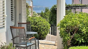 Een balkon met een tafel en stoelen, met uitzicht op een schilderachtige omgeving van een meer en bergen.