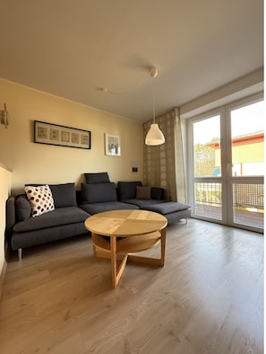 Una sala de estar moderna con un sofá, una mesa redonda de madera y una lámpara de techo.