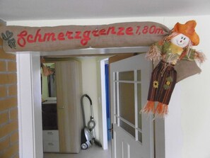 A doorway with a sign reading 'Schmertzzenze 1,80m' and a decorative figure. - Old fisherman's house, Germany (Mönkebude)