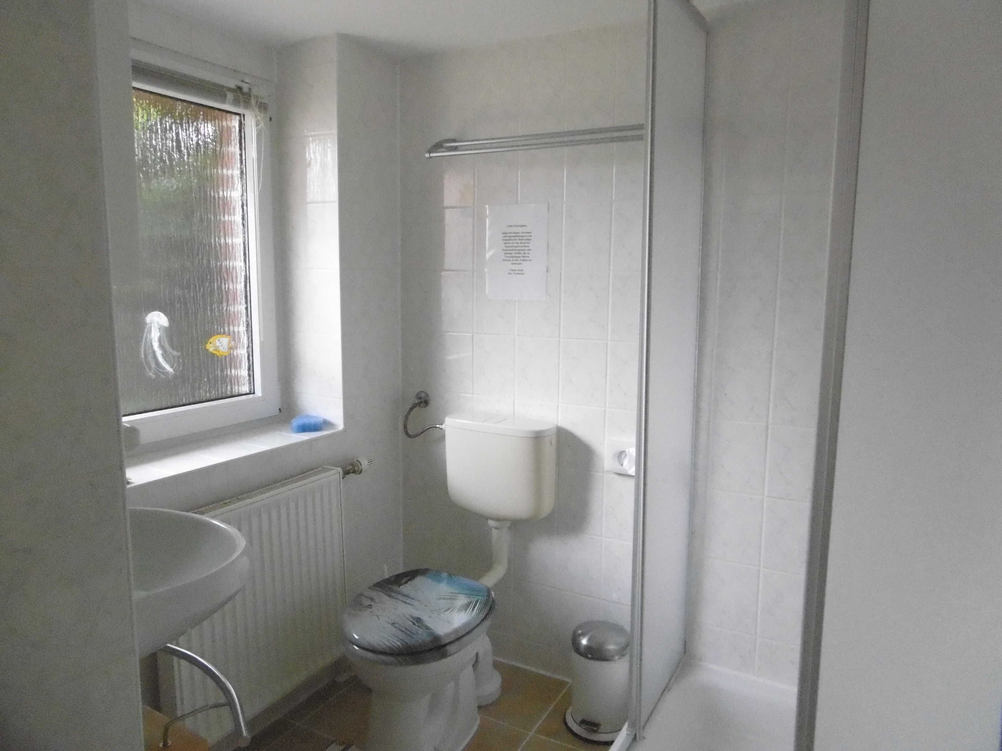 Un baño con inodoro, lavamanos, ventana y zona de ducha.