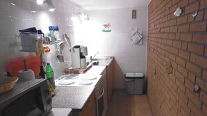 A kitchen with a microwave, stove, sink, and a trash bin. - Old fisherman's house, Germany (Mönkebude)
