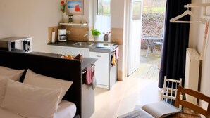 Ett kompakt hotellrum med ett litet kök, en säng, en matplats och utsikt över omgivningarna.
