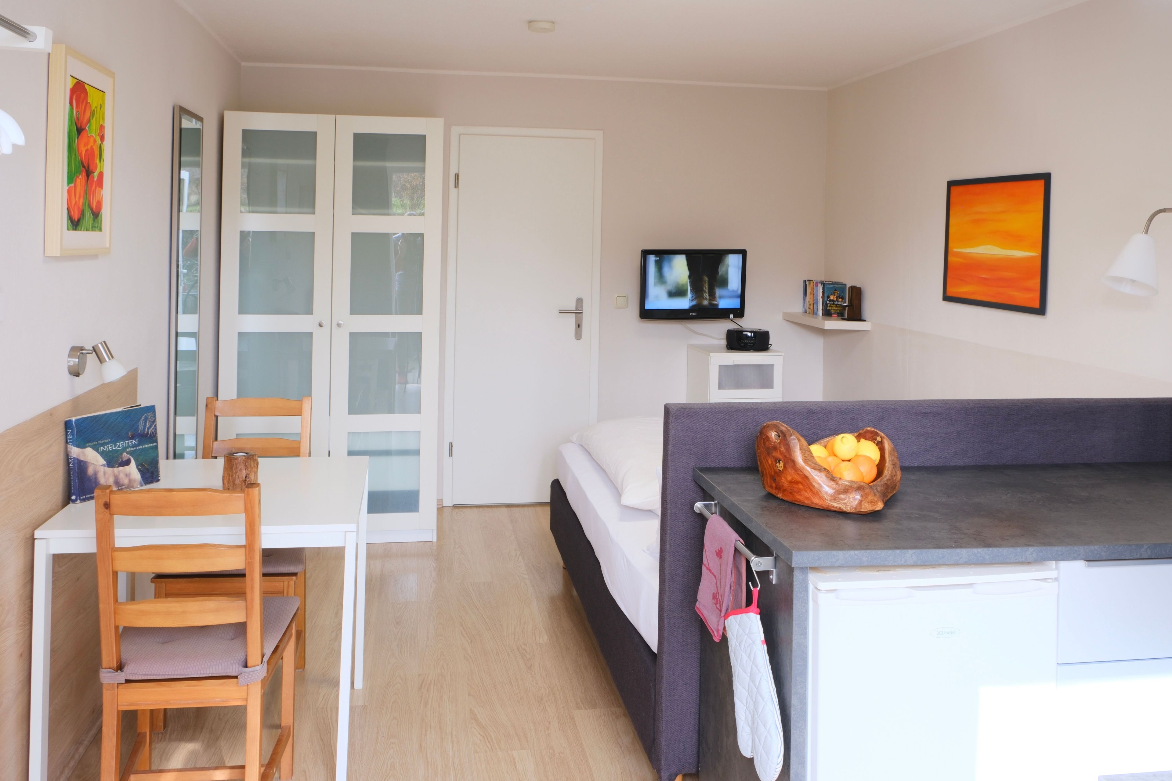 A room with a bed, a TV, a desk, and a chair.