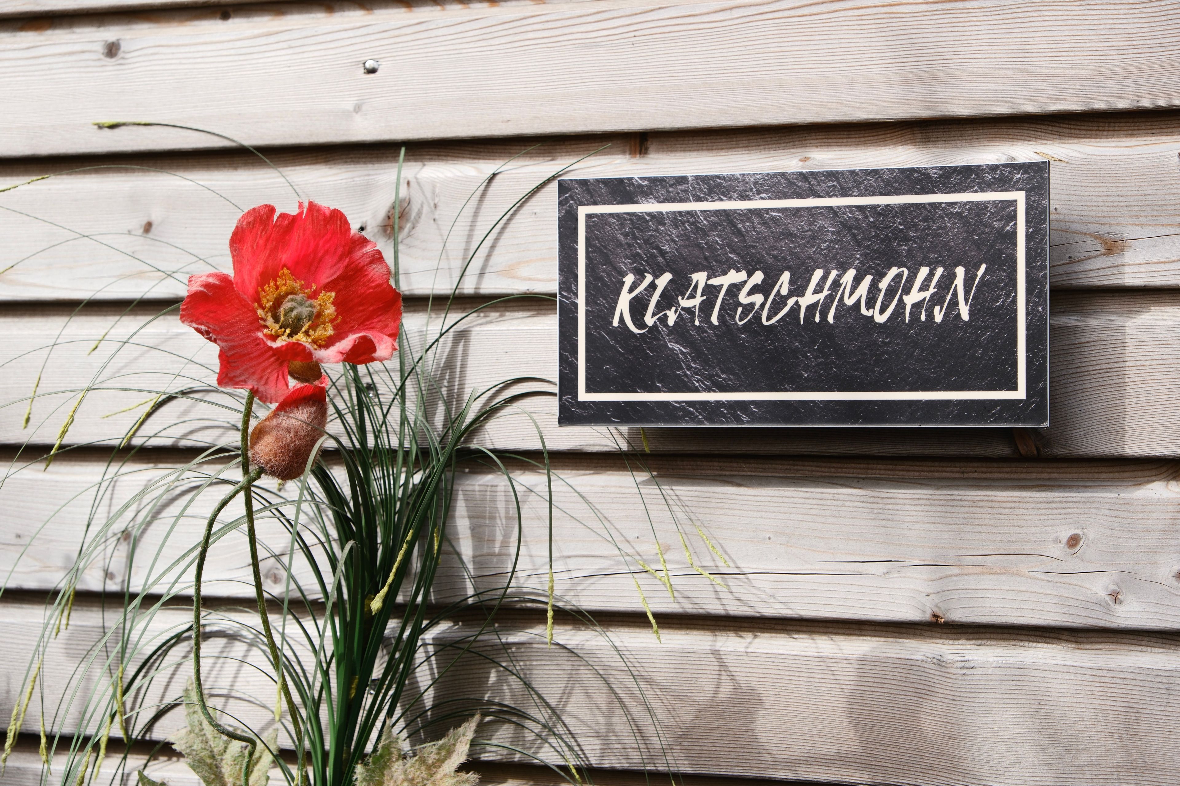 Un mur en bois sur lequel est affichée une enseigne portant l’inscription « KLATSCHMÖHN ».