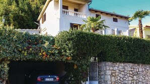 Une maison à deux étages avec un mur en pierre et une voiture garée dans un garage fermé.