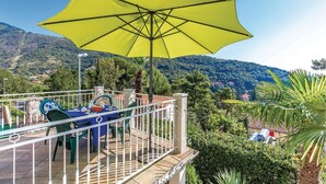 Une terrasse avec un parasol jaune, des sièges en plein air et une vue panoramique sur les montagnes.