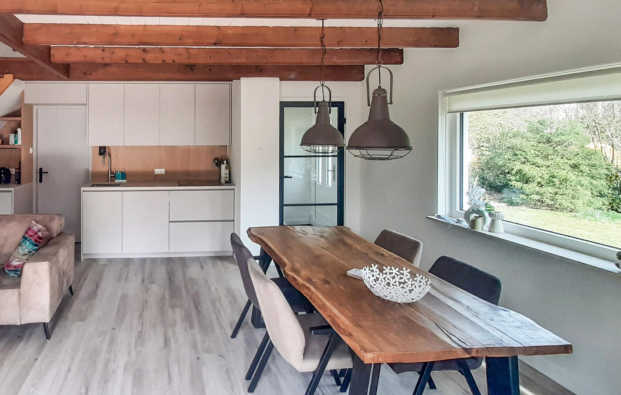 Una cucina moderna con mobili bianchi, un tavolo da pranzo in legno e lampade a sospensione.