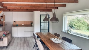 Una cucina moderna con mobili bianchi, un tavolo da pranzo in legno e lampade a sospensione.