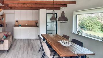 Una cucina moderna con mobili bianchi, un tavolo da pranzo in legno e lampade a sospensione.