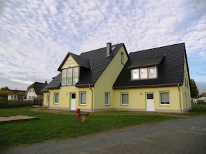 A two-story building with a sloped roof, a balcony on the upper floor, and a sign that reads "Haus Trifende".
