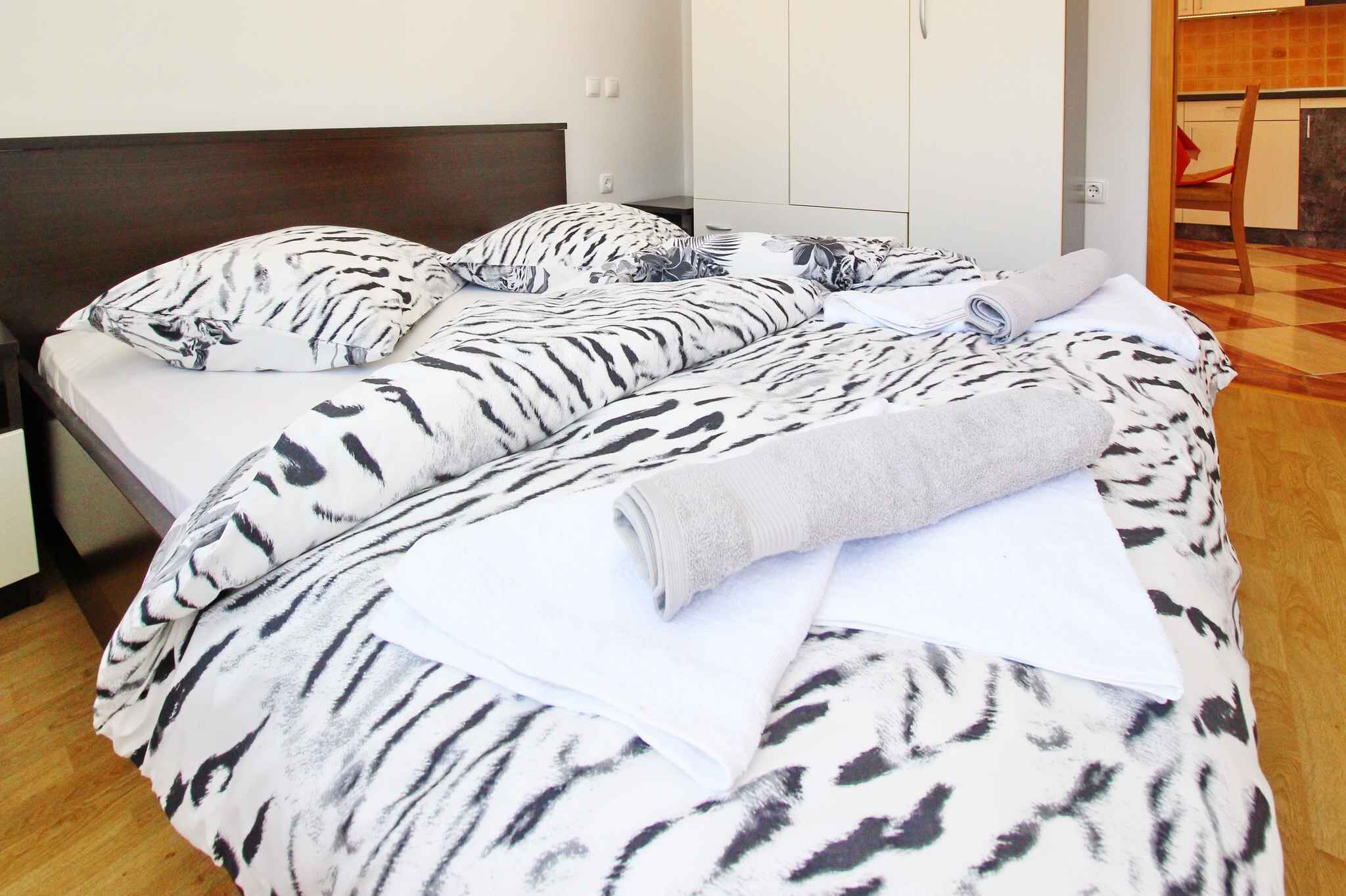 A bed with a zebra print bedspread, a wooden headboard, and a white pillow.