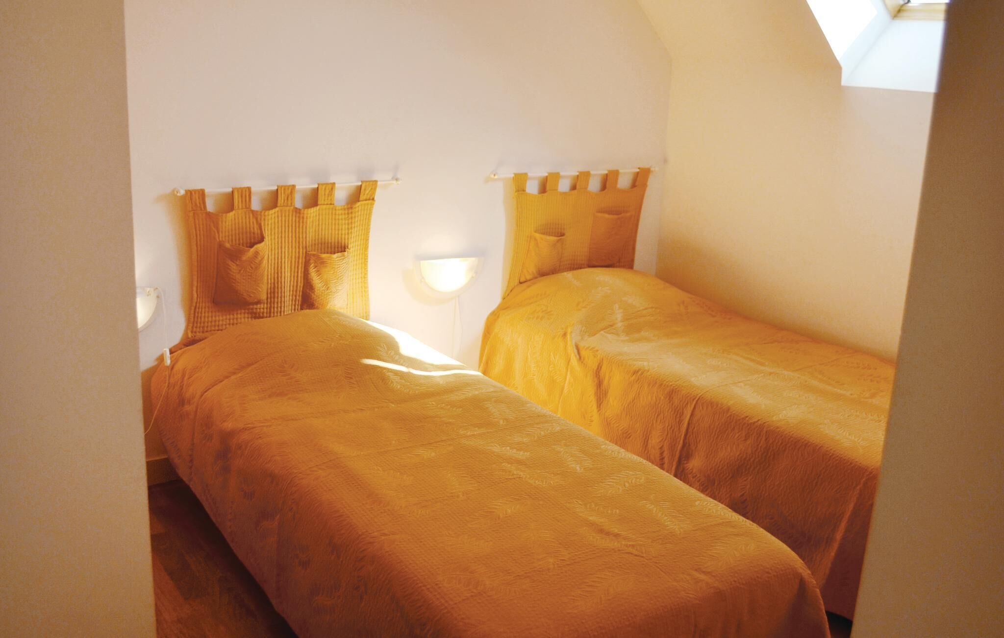 A small, cozy room with two beds, each with a headboard and pillows.