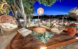 An outdoor seating area with wicker furniture, a round wooden table, and a decorative lantern. - Nice apartment in Imperia IM (Imperia IM)