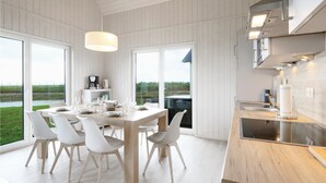 A modern kitchen with a large island, white cabinetry, and a view of the outdoors. - Amazing home in OstseeResort Olpenitz with sauna (OstseeResort Olpenitz)