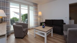 A modern living room with a sofa, armchairs, a coffee table, and a lamp.