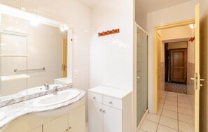 Ein modernes Badezimmer mit einem großen Spiegel, zwei Waschbecken und einem Waschtisch mit Schubladen.