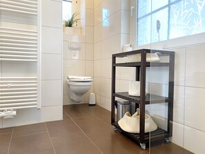Casa de banho moderna com sanita, um armário com toalhas e radiador.