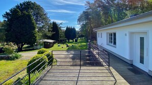 A pathway leading to a building with a white exterior, surrounded by greenery and trees. - Staphel - Ferienhaus Hete - dog-friendly, near the Baltic Sea - FH Hete (Sassnitz)