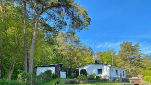 A house with a stone wall and a grassy yard, surrounded by trees. - Staphel - Ferienhaus Hete - dog-friendly, near the Baltic Sea - FH Hete (Sassnitz)