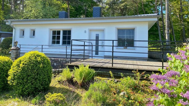 Un bâtiment blanc doté d’un balcon, entouré de verdure et d’arbres.